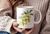 a woman holding a coffee mug with lemons painted on it