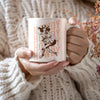 a woman holding a coffee mug with a picture of a cowboy on it