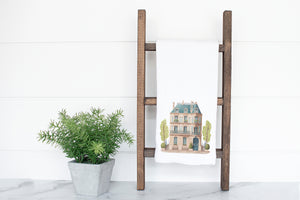 a towel rack with a house on it next to a potted plant