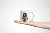 a hand holding a white coffee mug with a picture of a woman on it