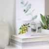 a white coffee mug with lemons on it sitting on a stack of books