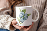 a woman holding a coffee mug with blue flowers on it