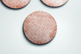 three pink and white buttons on a white surface