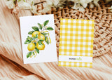 two cards with lemons on them next to a basket of flowers