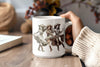 a person holding a coffee mug with a picture of three women on it