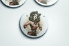 a set of three buttons depicting a woman with a gun