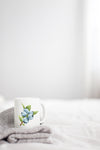 a white coffee mug with blue flowers on it