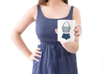 a woman in a blue dress holding a coffee mug