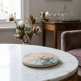 Detailed image of a sandstone coaster in a boutique hotel-style living room on a marble surface, highlighting texture and botanical artwork.